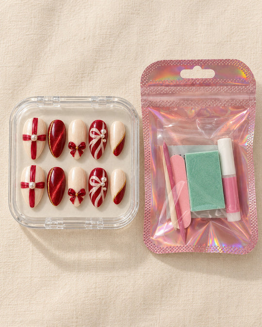 Giftwrap Crossing hand-painted press-on nails — in clear case beside application kit. Design preview.
